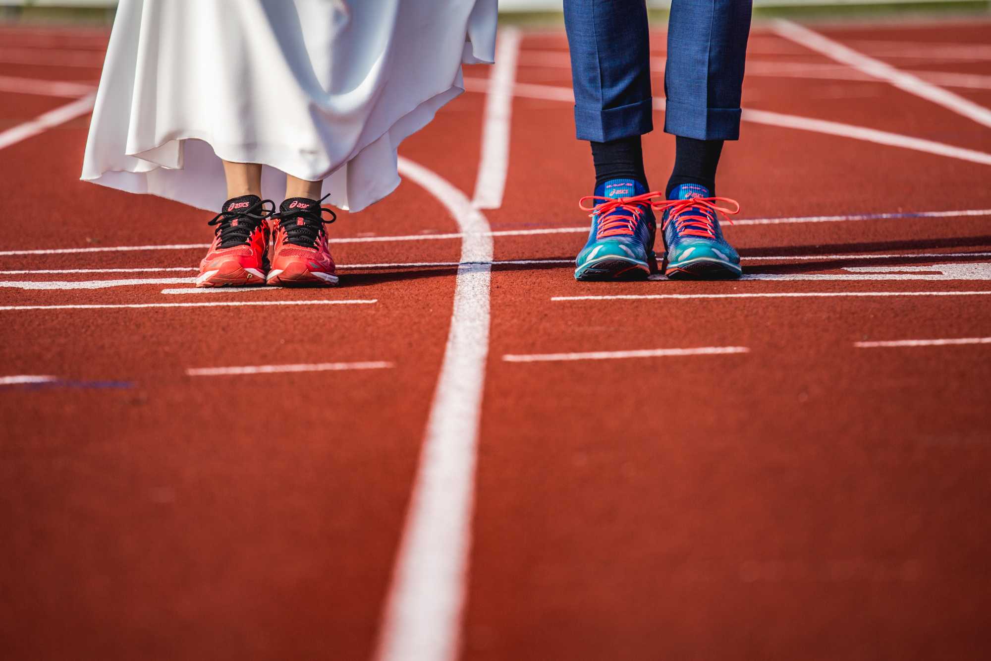 Voeten van bruidspaar in runners op de atletiekbaan.