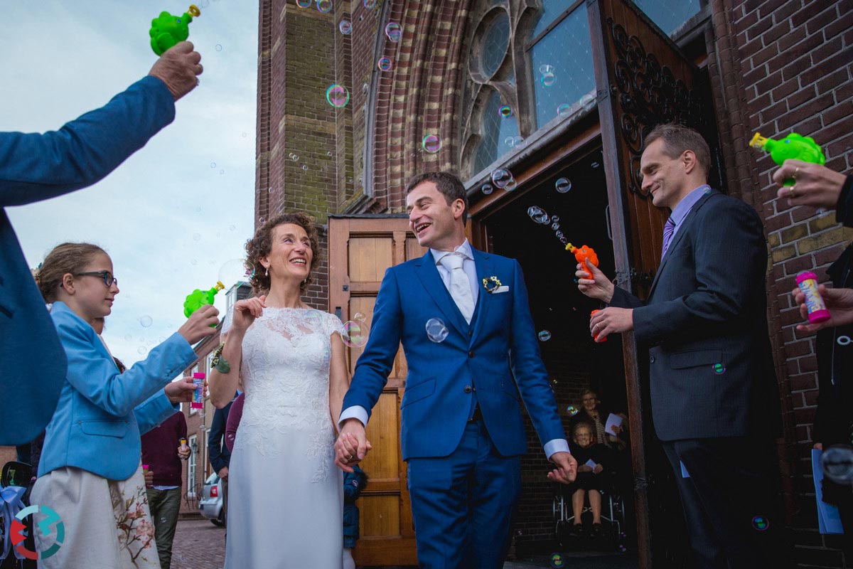 Bruidspaar komt de St. Clemens kerk in Waalwijk uitlopen.