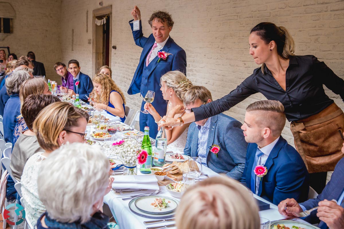 Sfeerbeeld van tafelende mensen tijdens een bruiloft.