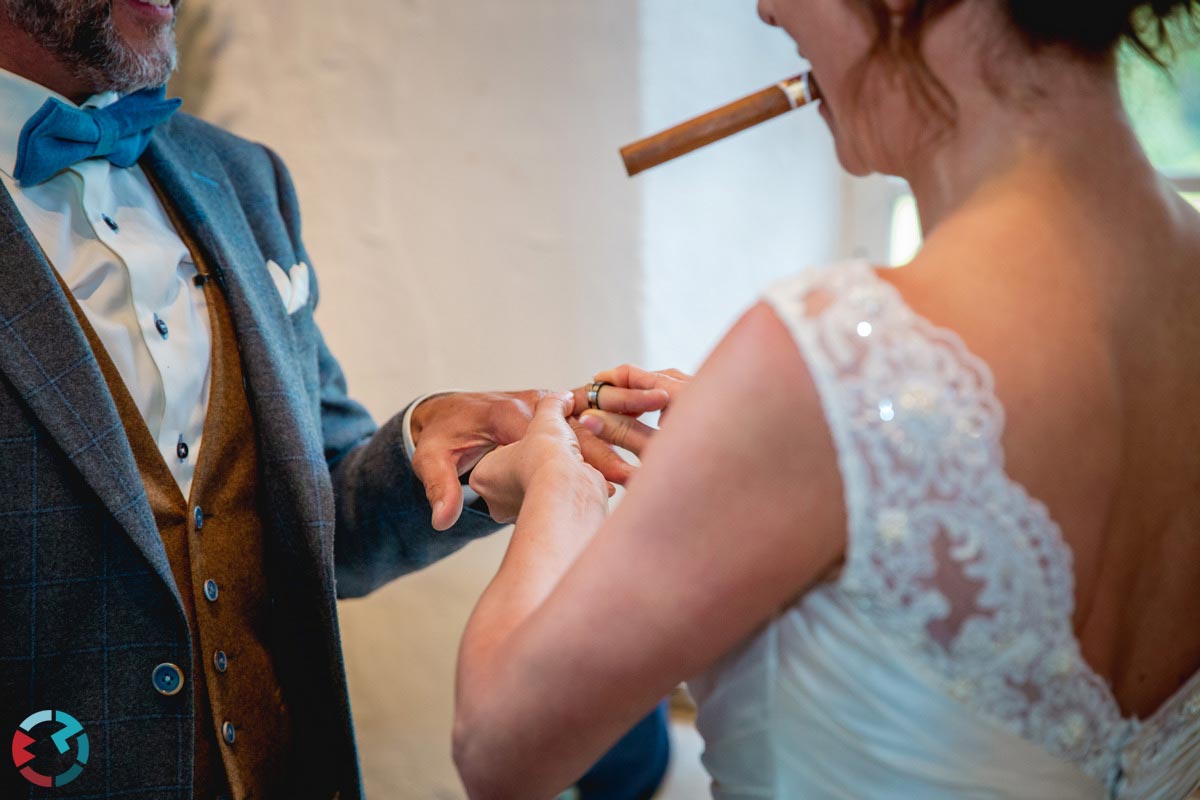 Bruid met sigaar in mond schuift ring aan vinger van bruidegom