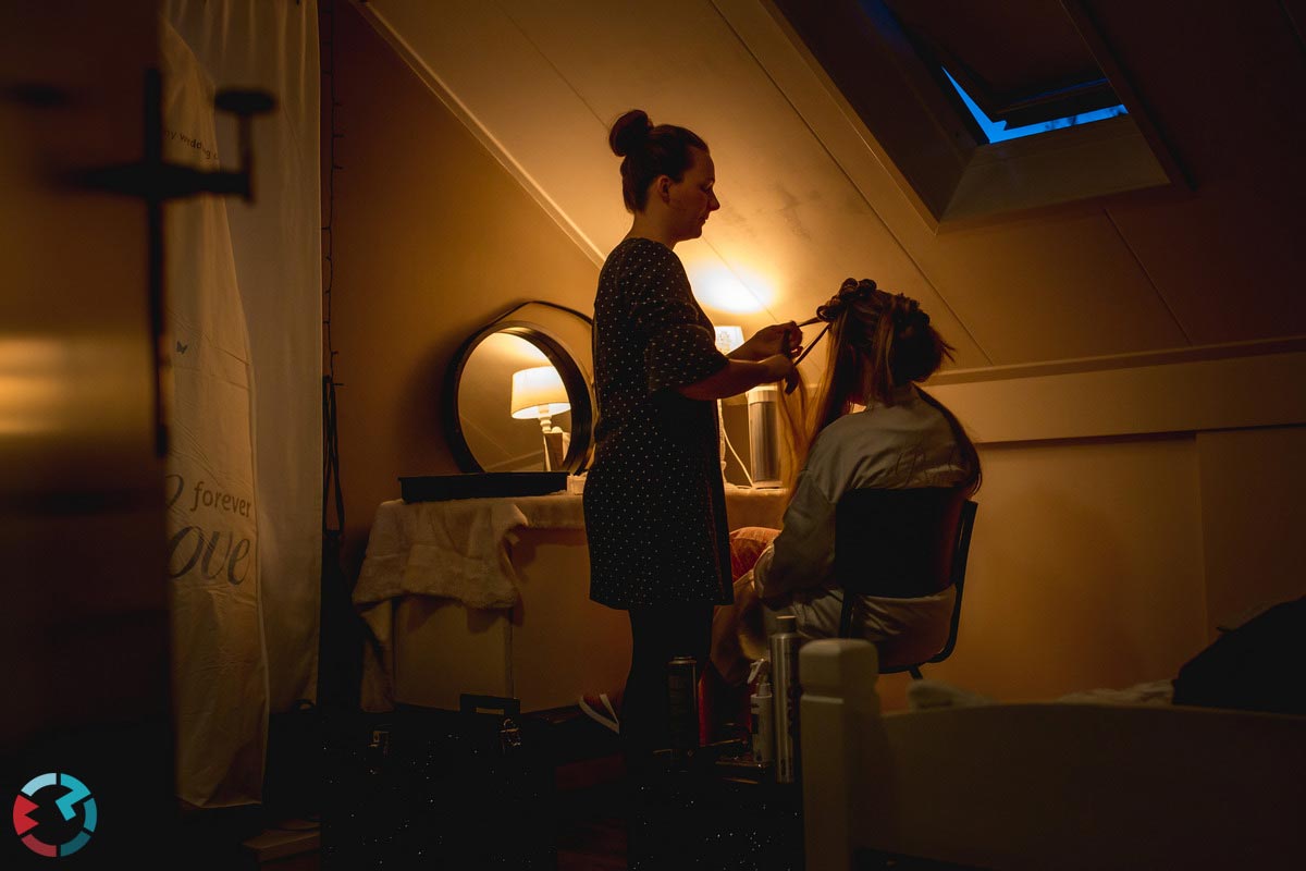 Visagiste doet haar van bruid op een donkere slaapkamer