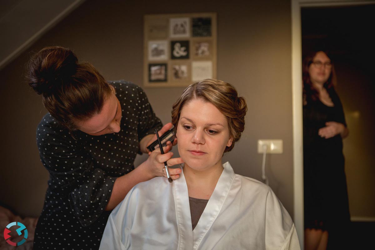 Visagiste brengt make-up aan bij bruid