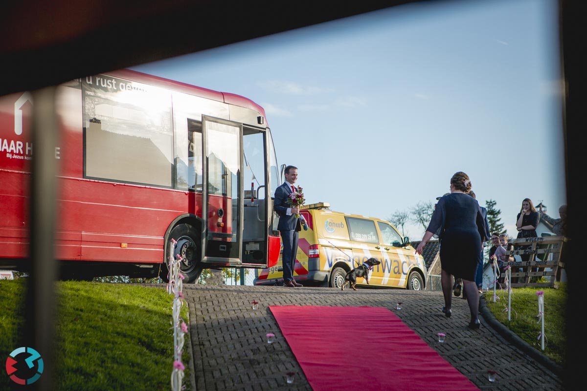 Bruidegom komt aan bij bruid met bus gasten wachten hem op