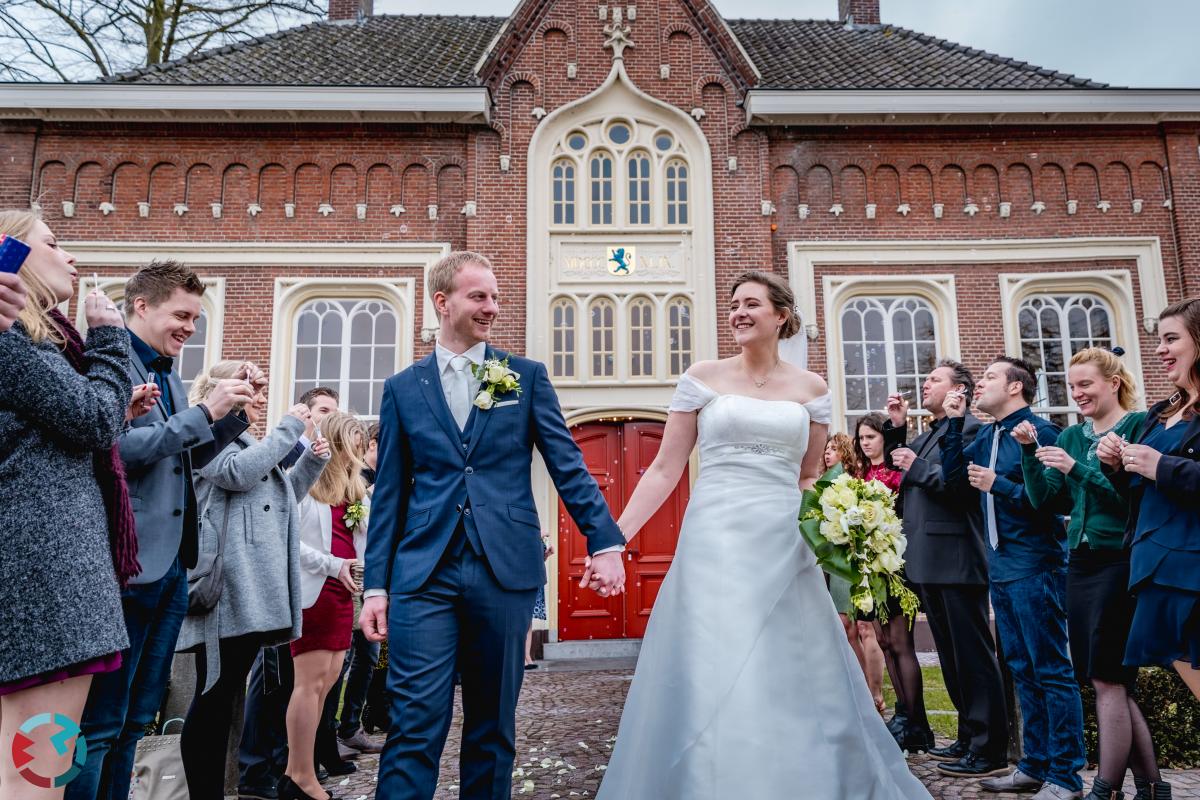 Bruidspaar loopt door haag van gasten bij het stadhuis van Udenhout