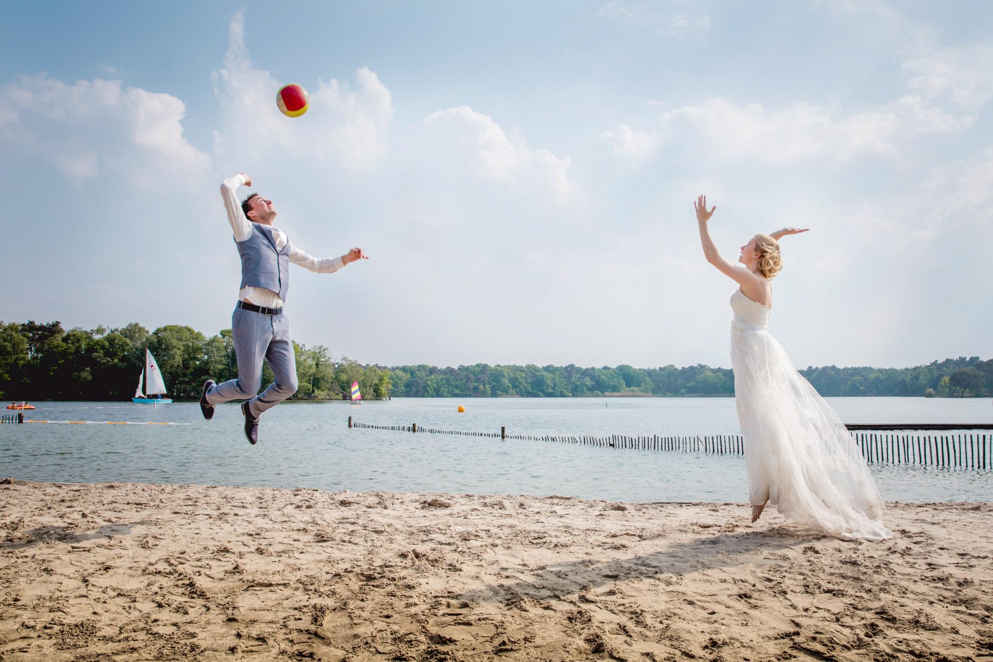 Bruidspaar speelt volleyball op een stand.