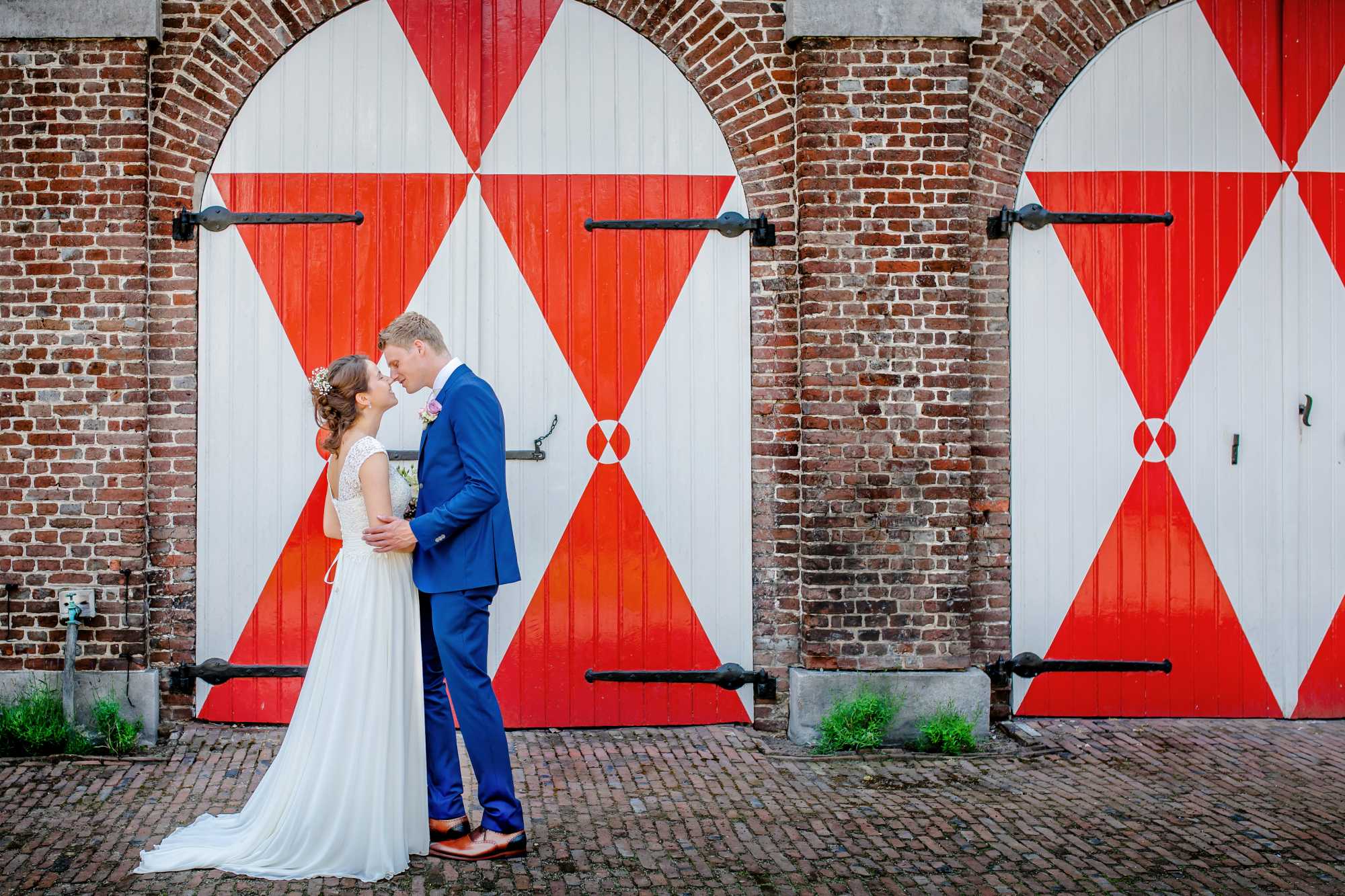 Reportagefoto van bruidspaar bij de deuren van Kasteel Heeze.