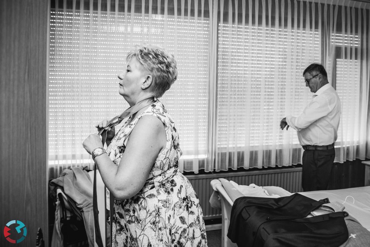 Moeder van de bruid strikt de stropdas bij haarzelf.