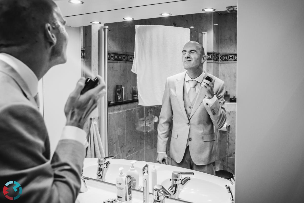 Bruidegom sprayt aftershave op.