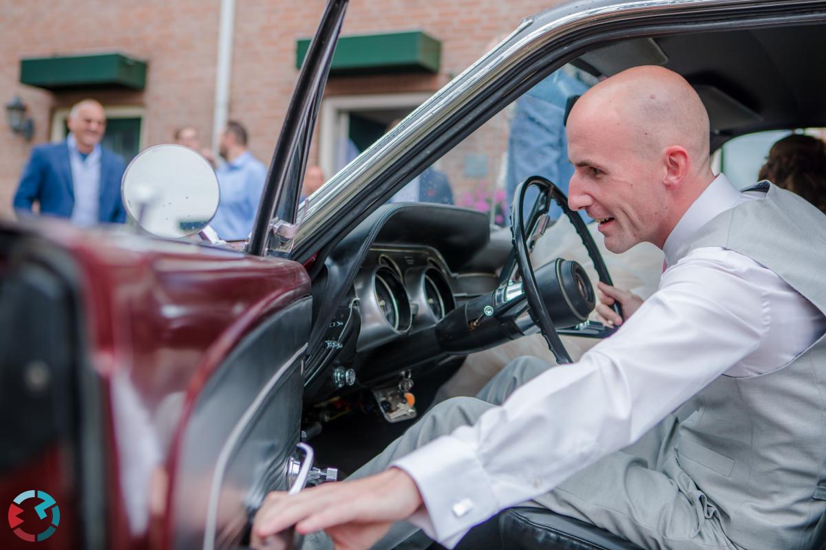 Bruidegom sluit deur van trouwauto.