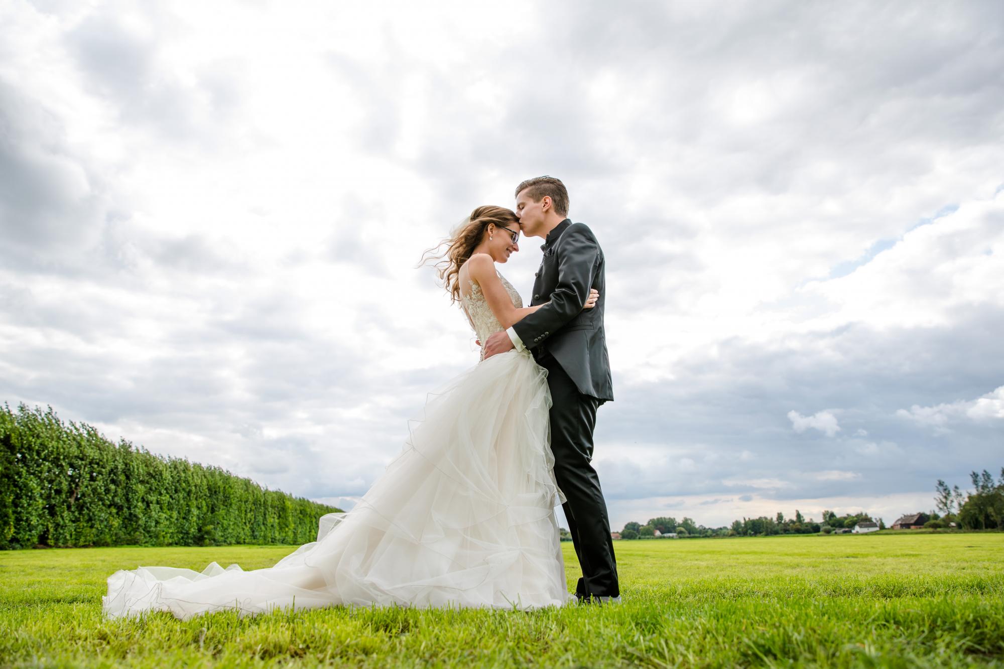 Reportagefoto van bruidspaar in een open veld.