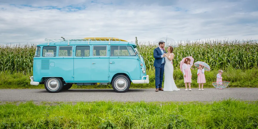 Bruidspaar poseert met een Volkswagen T2 busje en hun 3 kinderen voor een maisveld