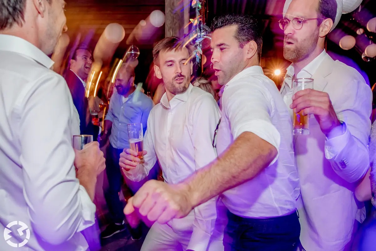 Mannen in witte blouse dansen uitbundig op het trouwfeest.