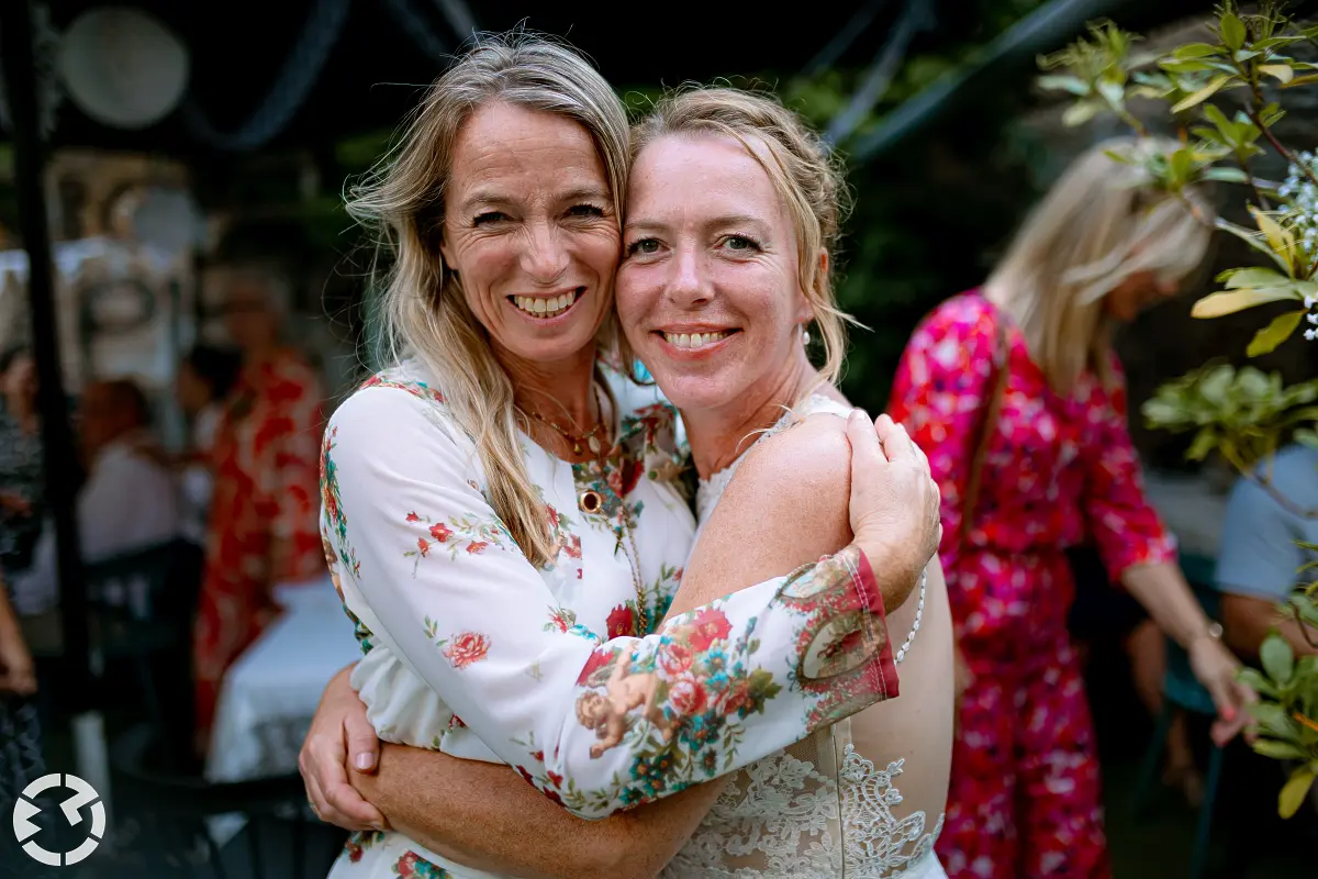 Bruid poseert met vrouw terwijl ze elkaar innig ontarmen.