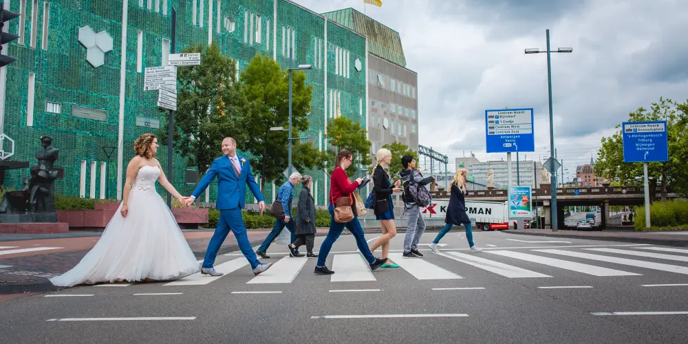 Bruidspaar loopt hand in hand over een zebrapad in Eindhoven centrum