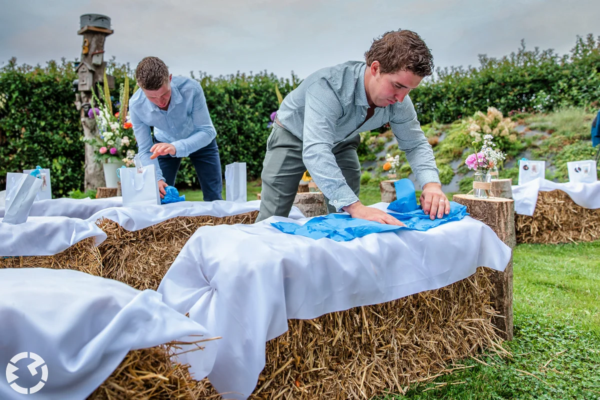 twee mannen drogen de kleden die op hooibalen liggen met uierpapier.