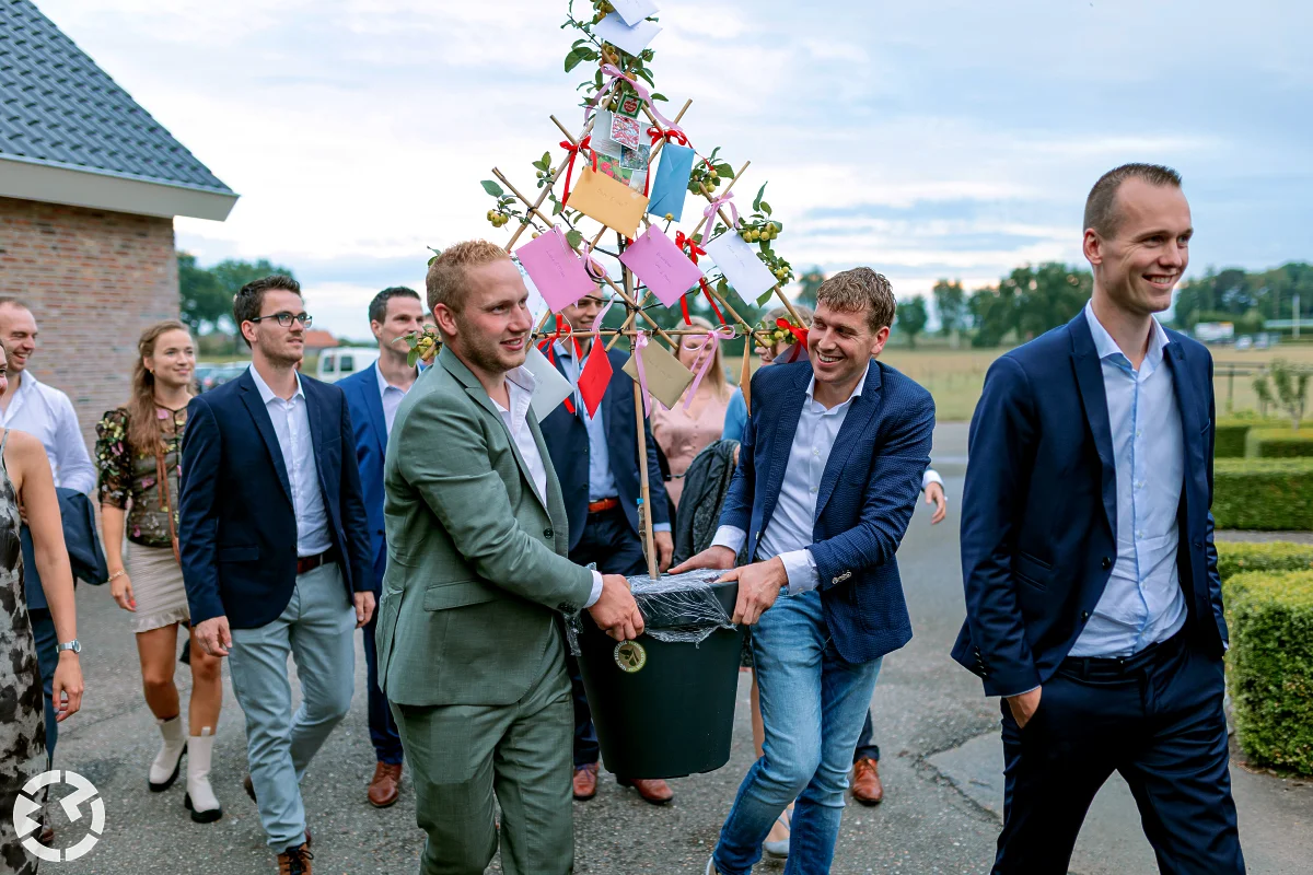 gasten komen aan op het feest en hebben jonge boom met enveloppen erin