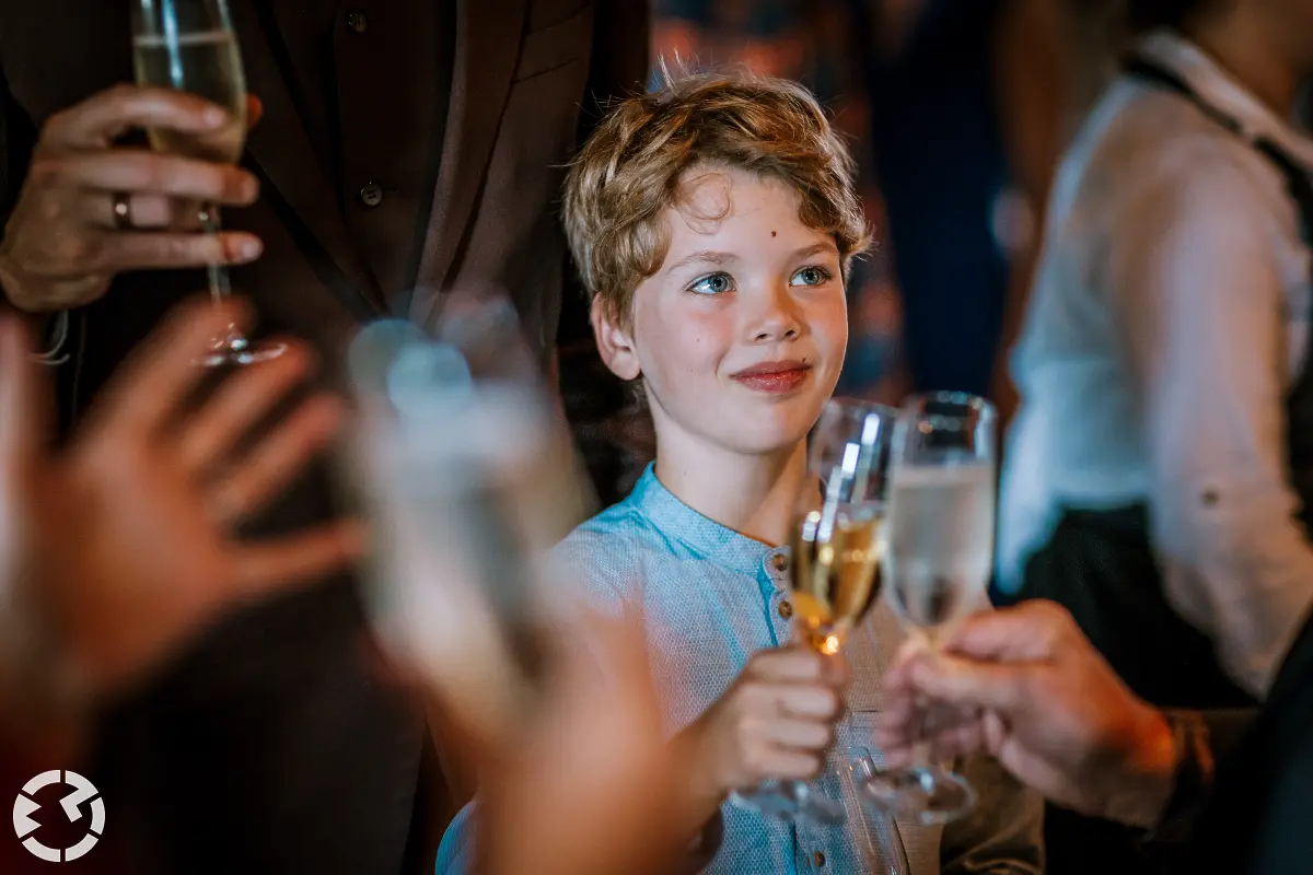 Kind tussen mensen met champagneglas proost met iemand anders.