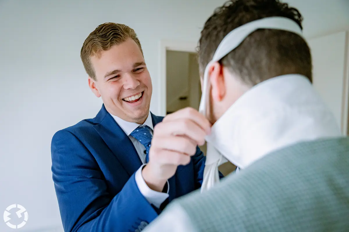 Man trekt stropdas over het hoofd van de bruidegom.