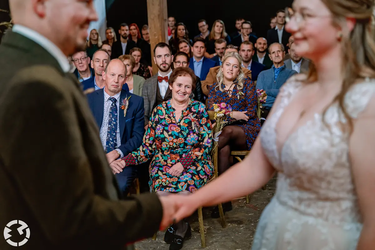 Gasten gefotografeerd door het bruidspaar dat elkaar de hand vasthouden tijdens het ja-woord.