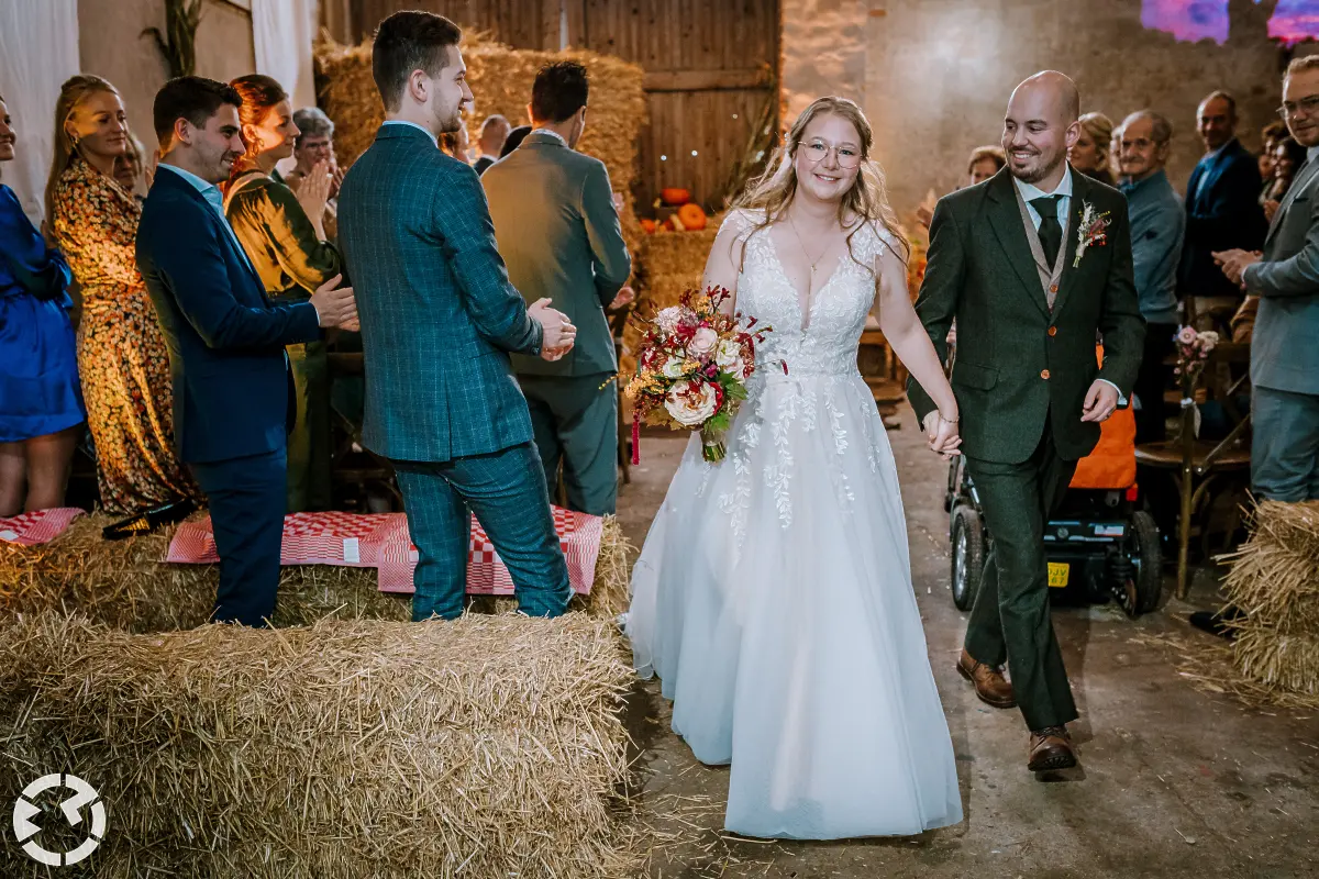 Bruidspaar loopt samen gelukkig lachend weg na de ceremonie in een stal.