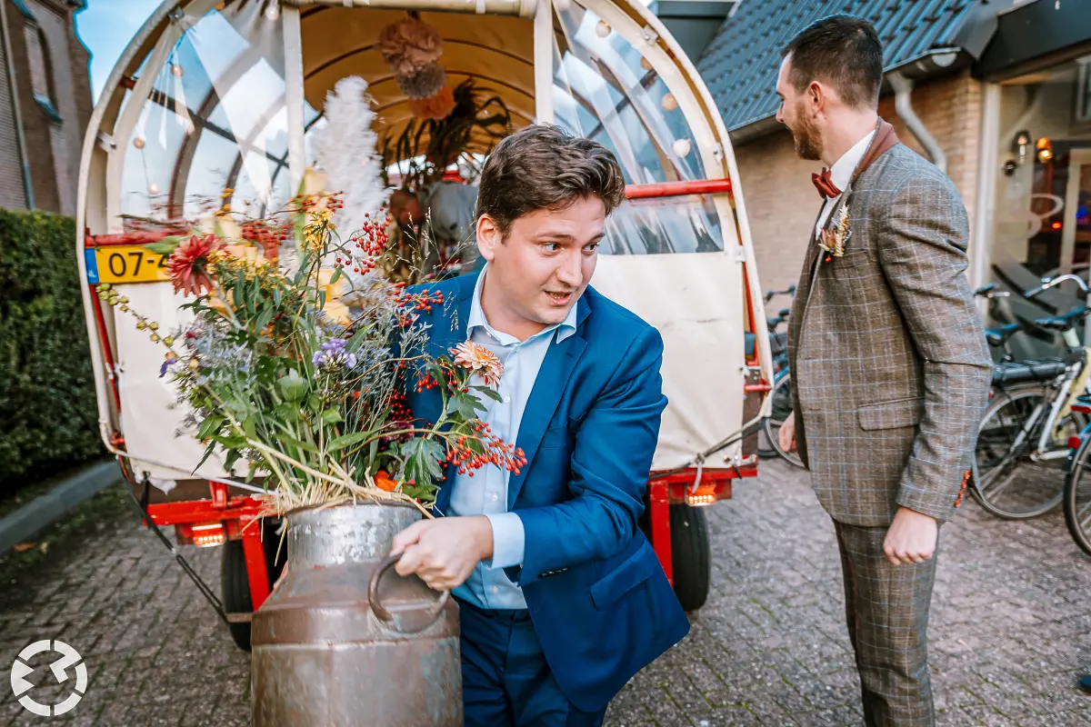 Jongen tilt melkkan met bloemen uit de huifkar bij Het Chaamse Wapen.