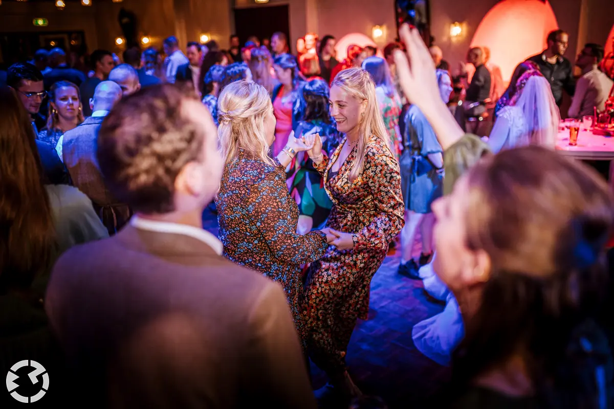 Op een volle dansvloer dansen twee vrouwen samen tijdens een bruidsfeest bij Het Chaamse Wapen in Chaam.