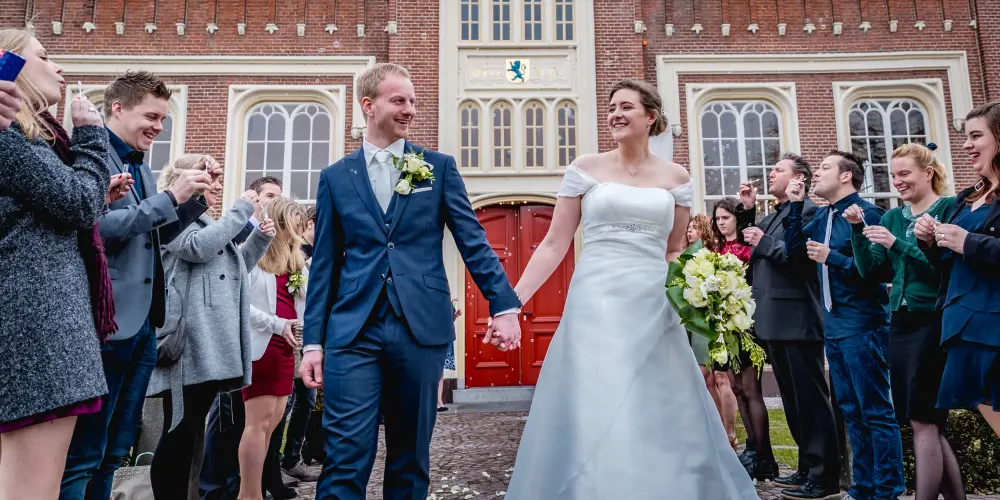 Bruidspaar loopt door gasten met Kasteel Strijdhoef op de achtergrond