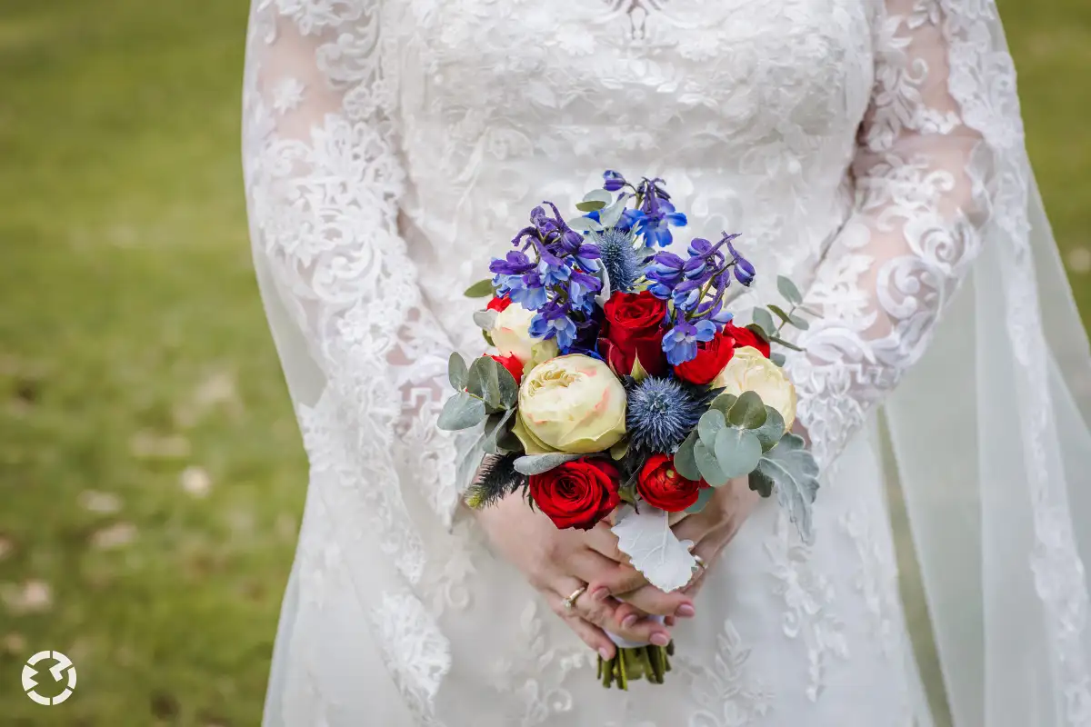 Bruidsboeket met rozen, ridderspoor, blauwe distel en eucalyptusbladeren.