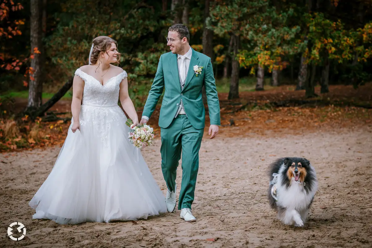 Bruidspaar loop met hun Rough Collie door wit zand in de herfst.