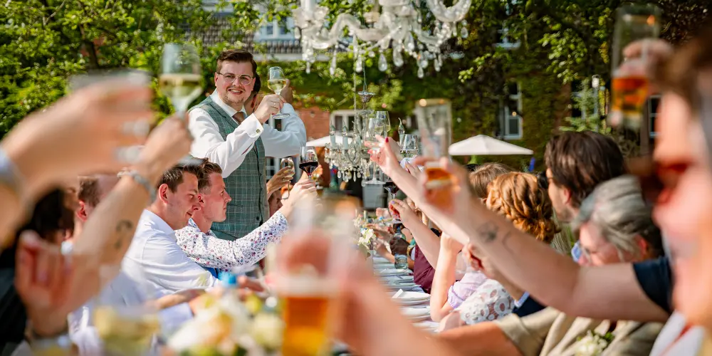 2 heren trouwen bij Klooster Nieuwkerk Brabant toast tijdens diner buiten zonnig gezellig