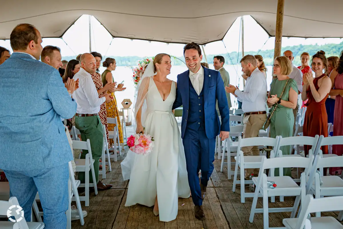Bruidspaar loopt hand in hand weg van ceremonie gezellige fotografie