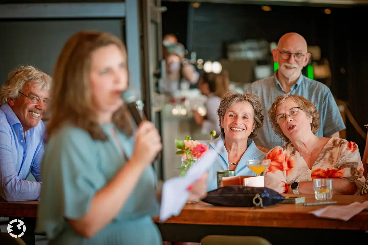 Ouders kijken met genot naar speech tijdens bruiloft bij Het Houtse Meer