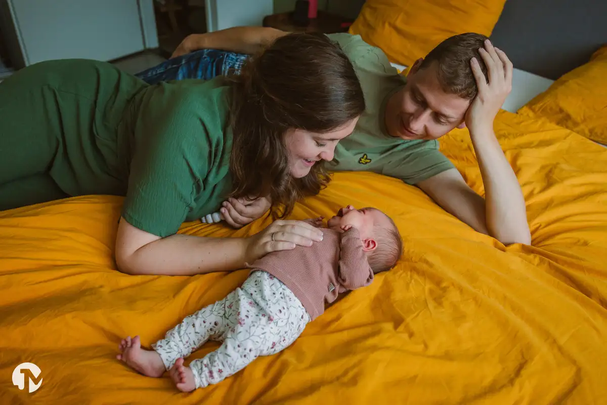 Pasgeboren meisje ligt tussen haar ouders tijdens lifestyle babyshoot