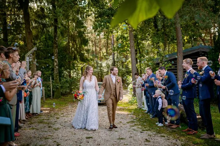 Bruidspaar komt aan op trouwlocatie in Otterlo en wordt door gasten ontvangen