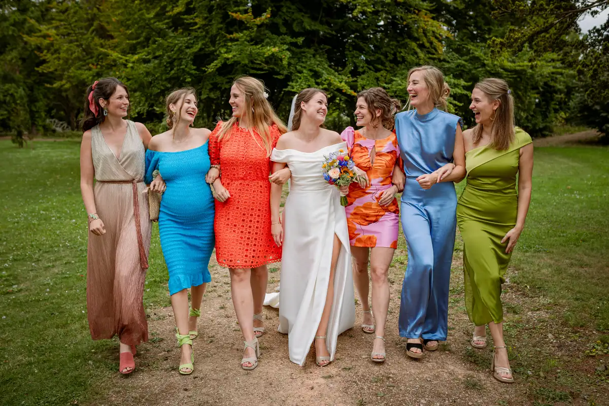 Bruid wandelt met haar vriendinnen tijdens de groepsfoto's op haar bruiloft.