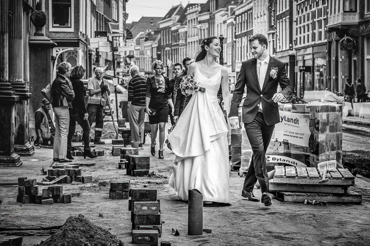 Bruispaar loopt genietend van elkaar door een opengebroken straat in de stad Leiden.