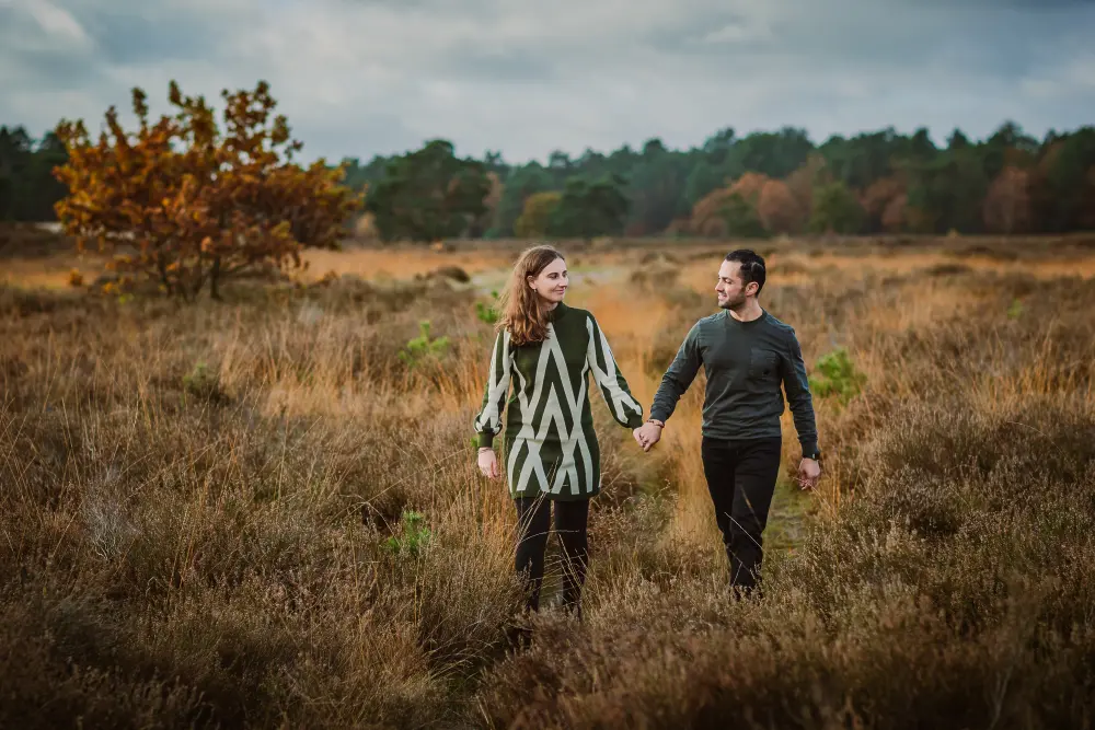 Fotoshoot van een man en vrouw lopend in een herfstig landschap