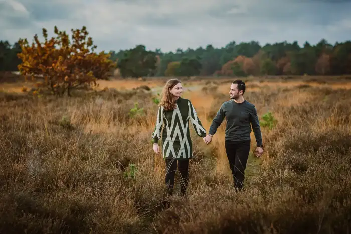 Fotoshoot van een man en vrouw lopend in een herfstig landschap