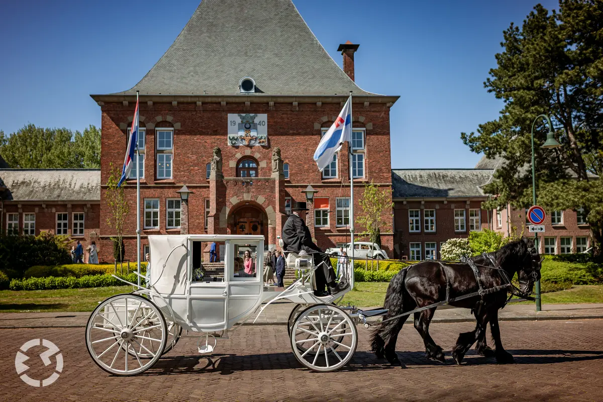 Witte trouwkoets komt aan bij het gemeentehuis van Leidschendam. 
